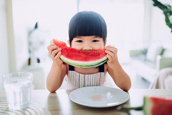 Asian toddler eating watermelon